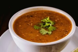 Warm bowl of lentil soup garnished with fresh cilantro leaves, perfect for cozy dining.